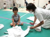 先生と3歳児が柔道衣を畳む様子